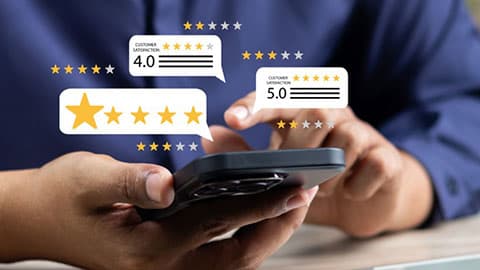 A person using a smartphone with star graphics representing online reviews popping out of the screen.