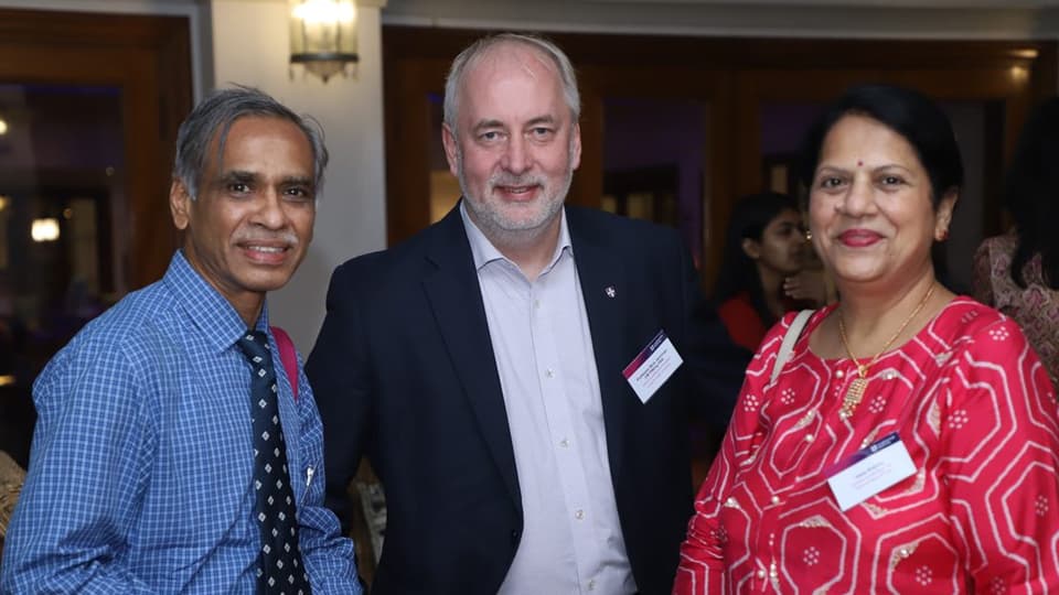 Two alumni guests stand with the Vice-Chancellor, Professor Nick Jennings at an alumni event in Mumbai in 2022. The three of them face towards the camera, smiling.