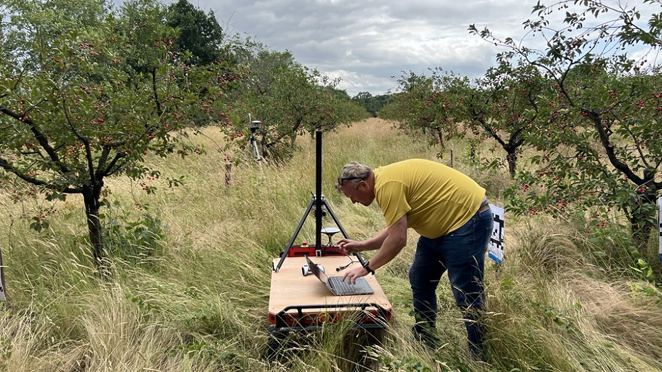 A man in a field examining an autonomous device to support UK horticulture