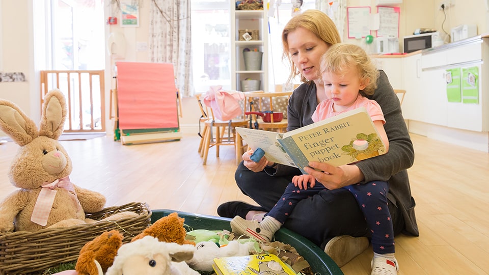 Adult reading to child in Discoverers room at Loughborough University Nursery