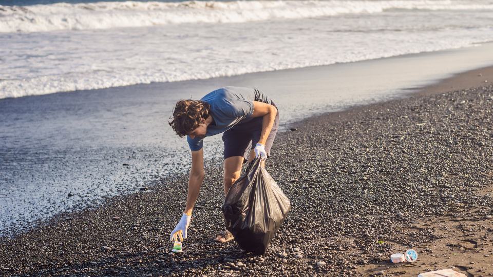 Man picking up litter on a pebble beach