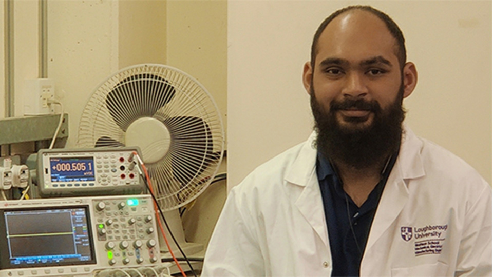 Sayed, sitting in a lab wearing a lab coat where equipment can be seen on the worktop in the background.