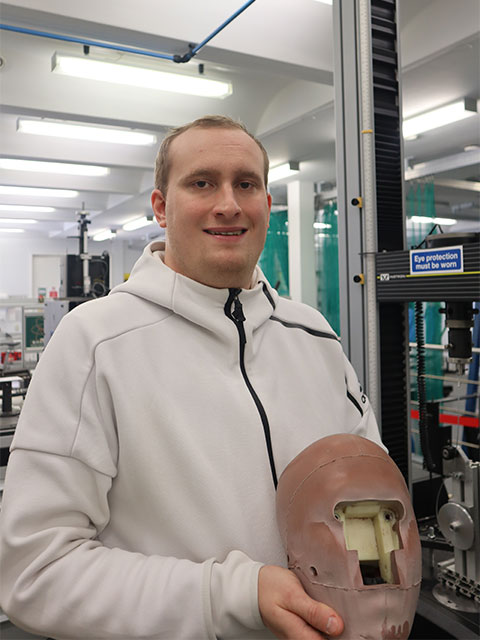 Portrait image of Rory holding a human head test prototype in the Sports Technology Institute. 