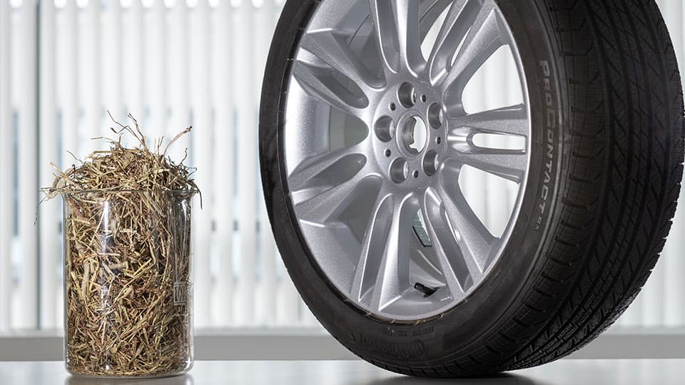 A beaker containing straw beside a tyre.