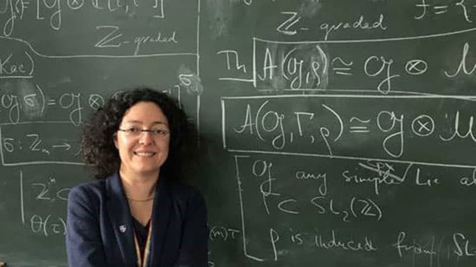 Sara Lombardo in front of a chalkboard with mathematical formulae