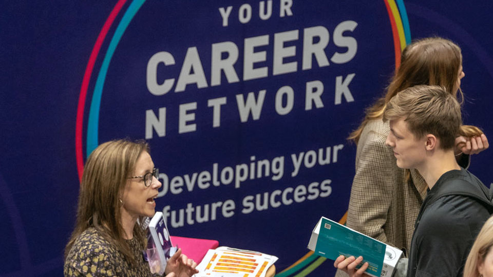 Careers Fair discussions between student and careers staff in front of the Your Careers Network background banner.