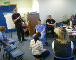 An engineer discusses the new mirror with stakeholders, midwives and (seated) a new mum