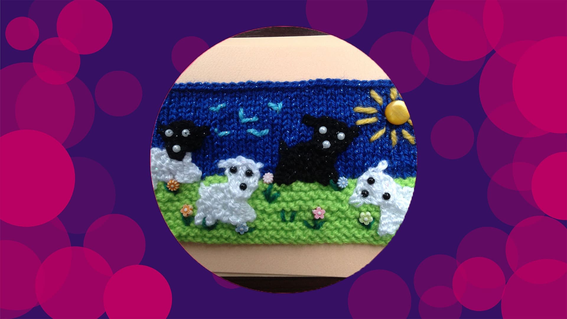 A knitted piece of fabric of sheep in a field and the sunshine in the sky on a blue background with green grass.