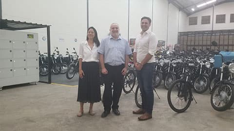 Three staff members at Arc Ride are standing in front of a crowd of bikes and smiling at the camera.