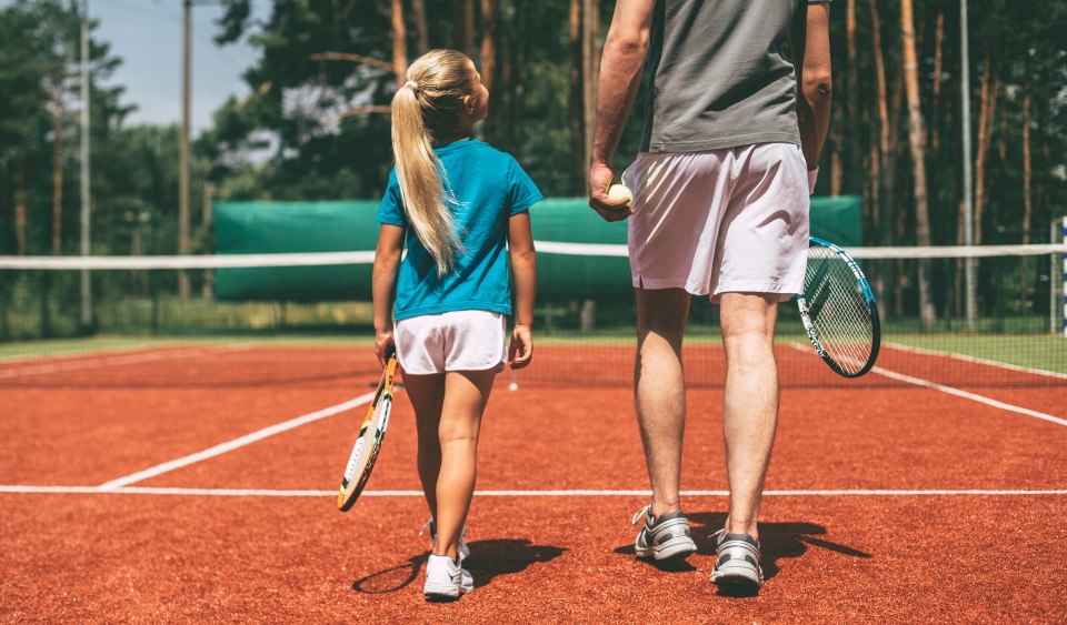 A father and daughter prepare to play a game of tennis
