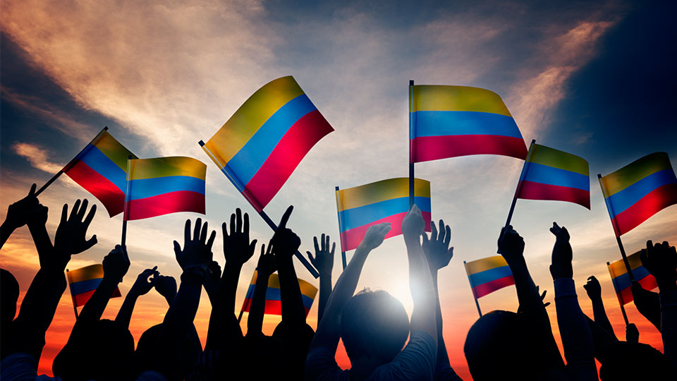 Pictured is a group of people waving the Colombian flag. 