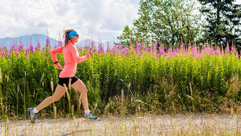 Pictured is a woman running next to a field of flowers.