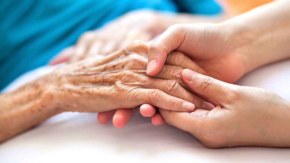 A young person holding an old person's hand
