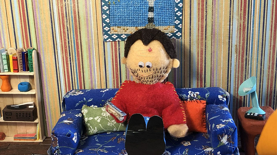 image of handmade puppet sat on a handmade sofa in a room created by student Amy Begent