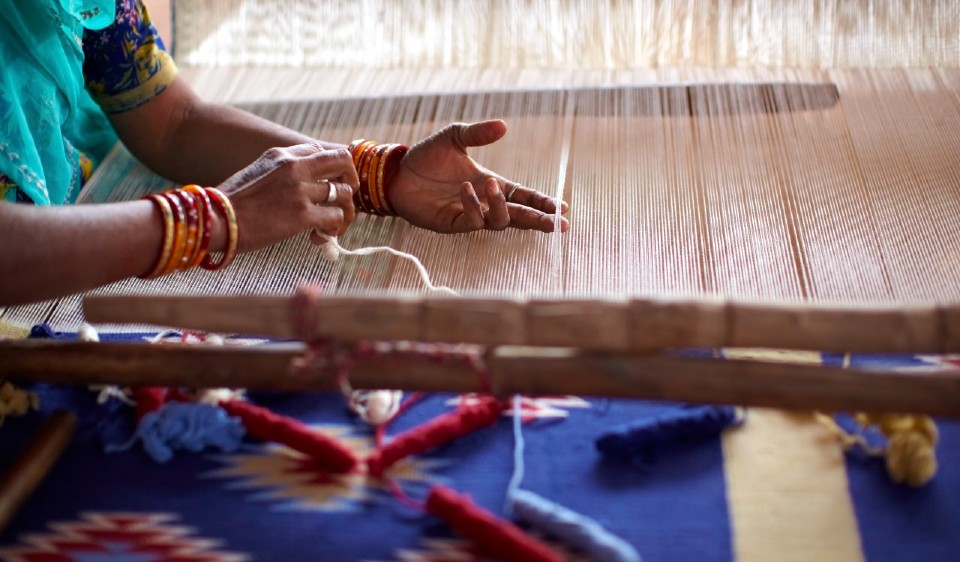 A woman weaving fabric. 