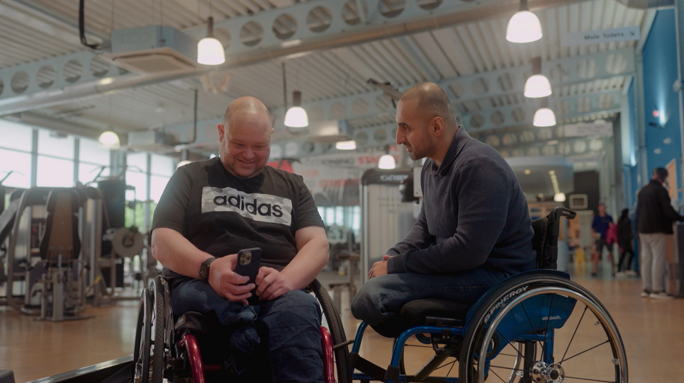 Two wheelchair users looking at a phone 
