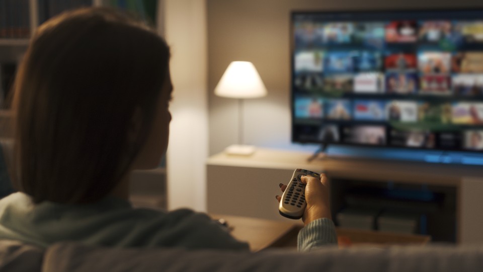 A woman watching TV holding a remote