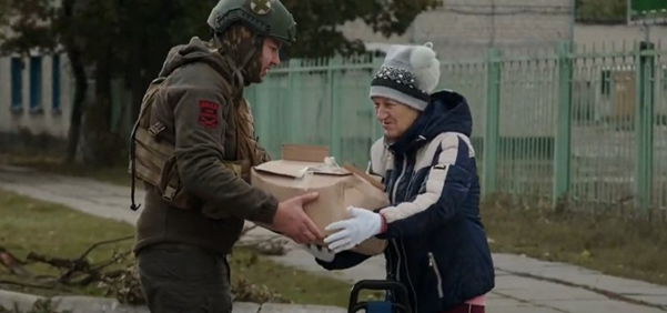 Aid worker hands parcel to Ukrainian woman