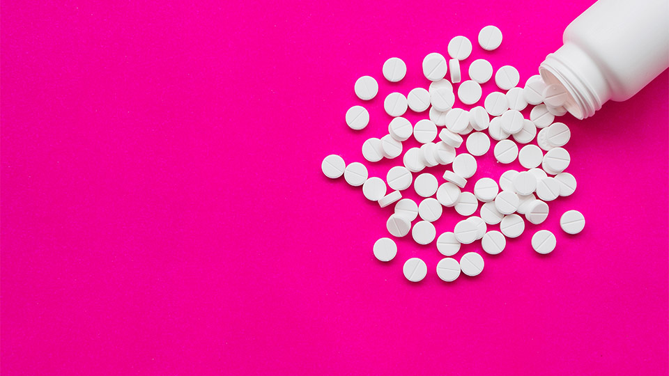 Pictured is a bottle of pills on a pink background. 