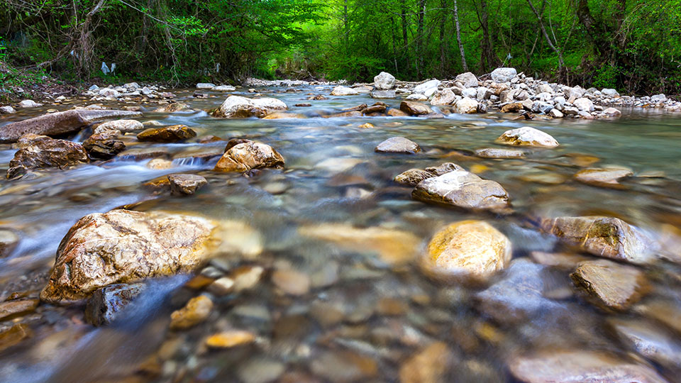 photo of riverbed with water flowing over rocks 
