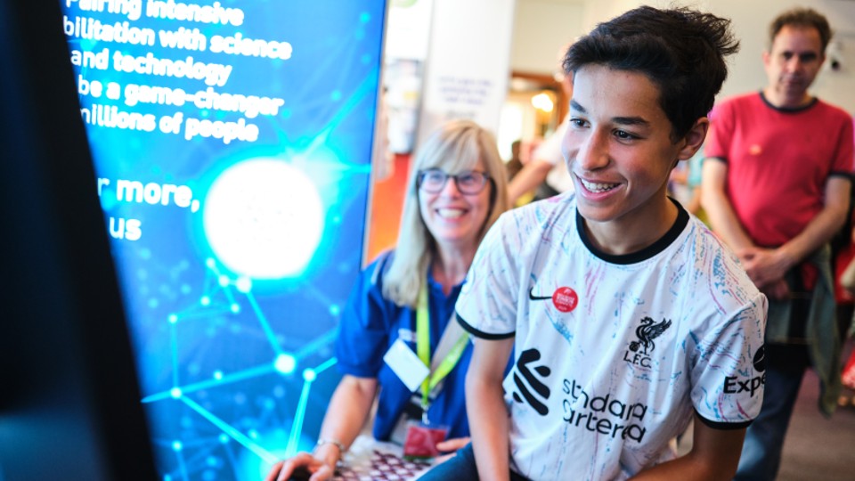 a boy smiling while taking part in a computer game at the NRC exhibition stand