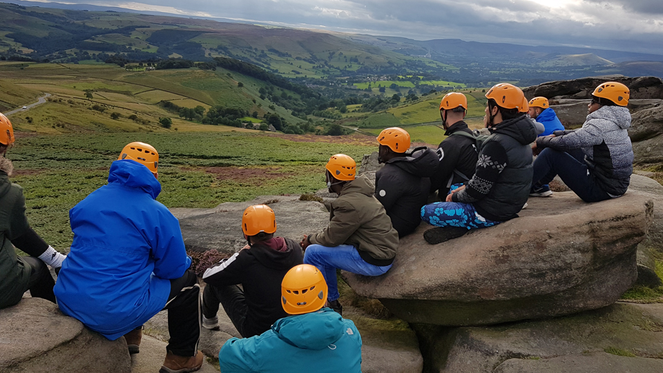 Young people enjoying a Bacca activity, sitting enjoying the view across ruggedhilltops