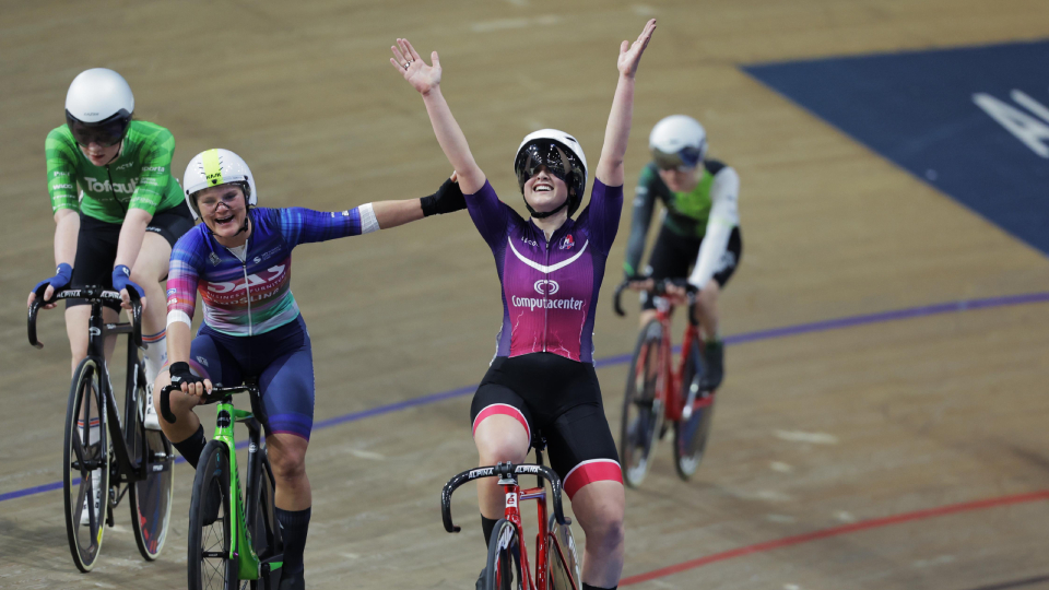 a cyclist celebrates a win with her arms in the air