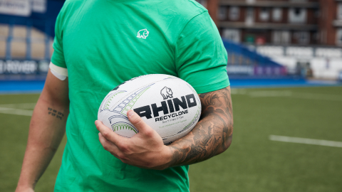 a man in a green t-shrt holding a rugby ball