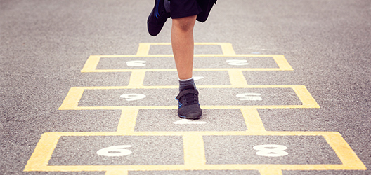 Pictured is a child doing hopscotch. 