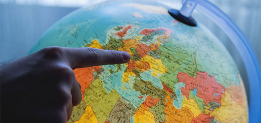 photo of a globe with someone pointing to a specific country 