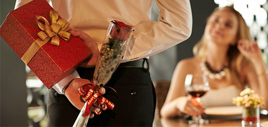 photo of man holding roses and a box of chocolates for his partner