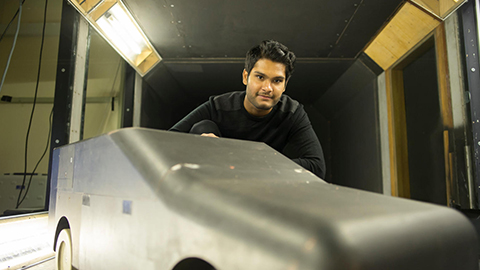 a student with a model car in the wind tunnel