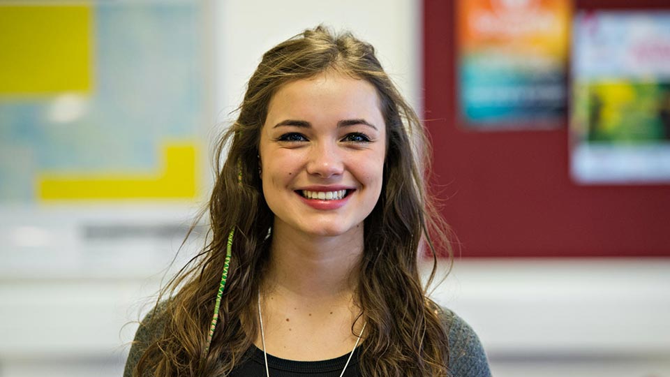 Close-up headshot of student Phoebe, smiling, looking directly into the camera. 