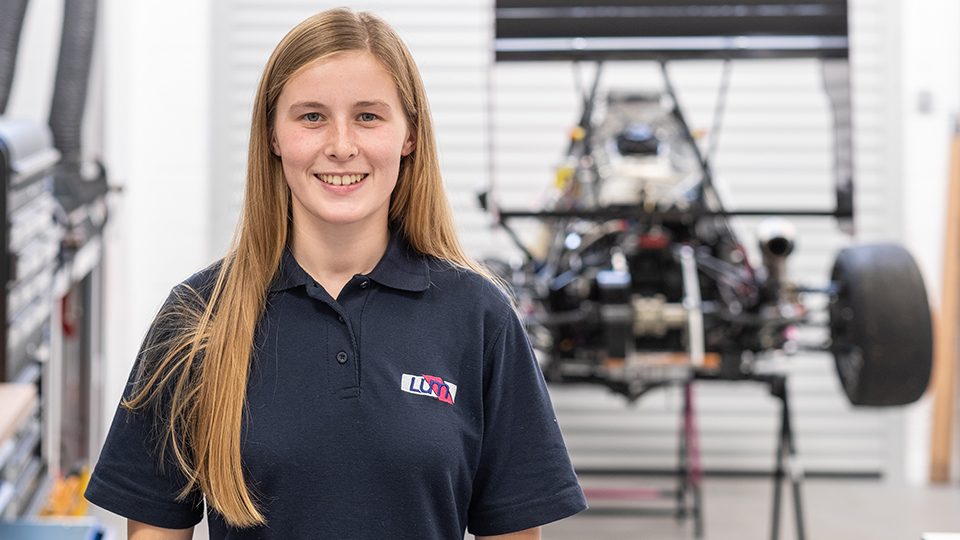 Danielle standing in front of a project car.