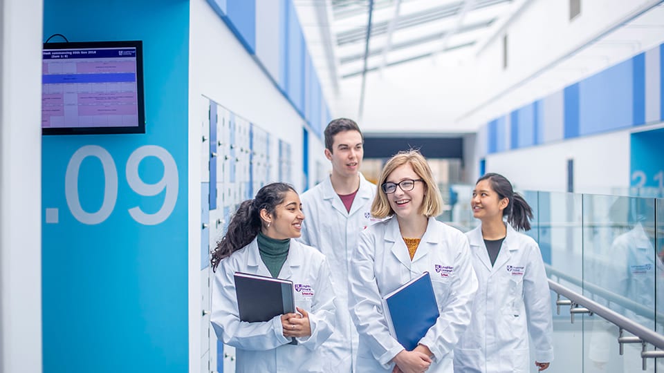 Group of students in white lab coats walking together