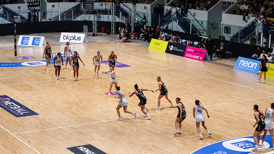 a zoomed out photo of a full netball court with Panthers playing a centre pass