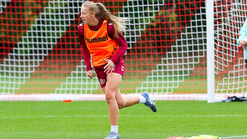 Ella West running on a football pitch