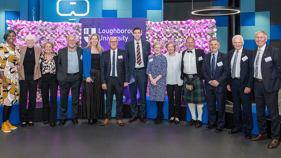 A large group of people standing in a row against a brightly coloured background