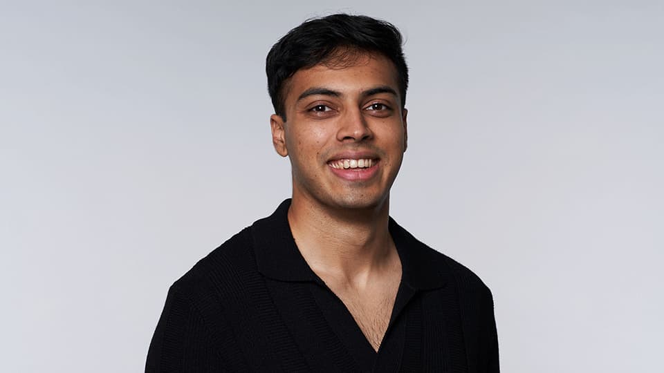 A headshot of Abhi Ghavalkar. He is wearing a black shirt and smiling at the camera.