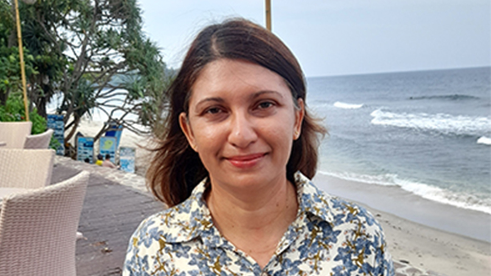 Picture of Diane smiling with the beach behind her