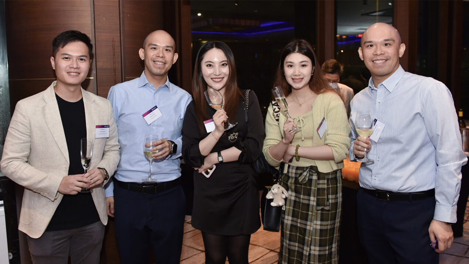 Five people standing together smiling and holding drinks at a reception in Hong Kong SAR in 2023