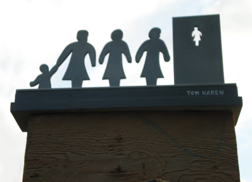 Sculpture of three ladies and a child queuing at a door featured on roof of a building. 
