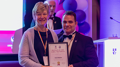 Two people standing smiling, holding a certificate