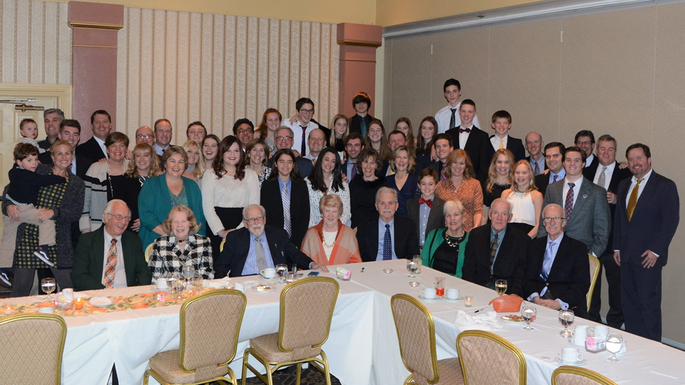 A group of people posing for a family photo, some seated at a table