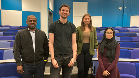 Four people stand together in the seated area of a lecture theatre. Left to right: Vijay Chithambaram, Jack Dabbs
Melissa Feaviour, Hunaynah Abdulgafar