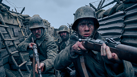 Three people in a trench with guns. They wear helmets.