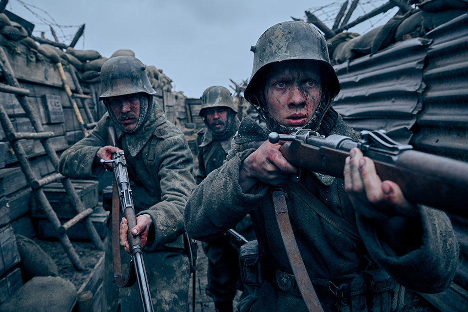 Three people in a trench with guns. They wear helmets.