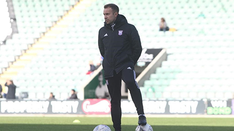 Charlie Baxter at a football stadium, standing on the pitch with two footballs at his feet