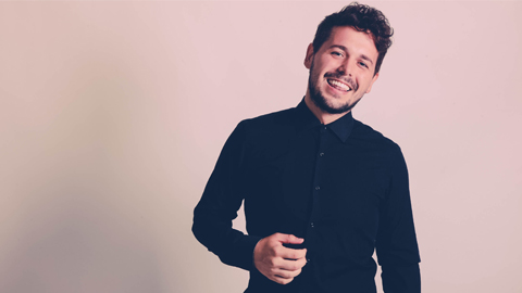 Professional photo of Tom Stevenson, who is wearing a navy, button-up shirt and smiling to the camera.