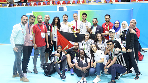 A group of people posing in various ways in a sports hall.